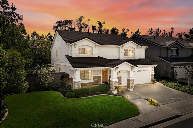 view of front of property with a lawn, an attached garage, stone siding, driveway, and a tiled roof