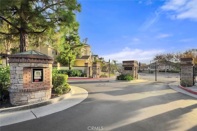 view of road featuring curbs, a gated entry, and a gate