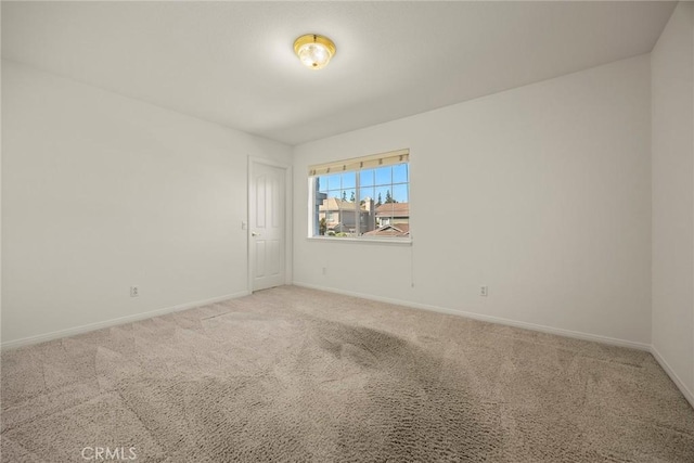 carpeted empty room featuring baseboards