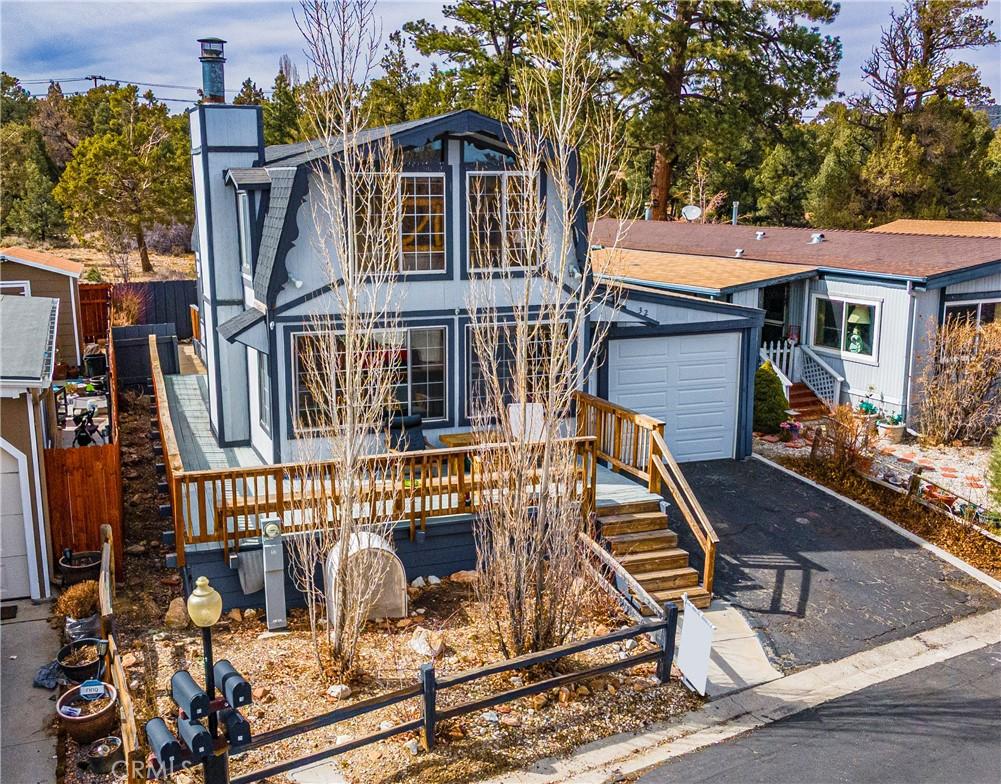 view of front facade featuring an outbuilding, aphalt driveway, a chimney, and fence