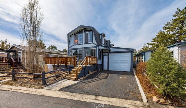 view of front facade featuring driveway, an attached garage, and a wooden deck