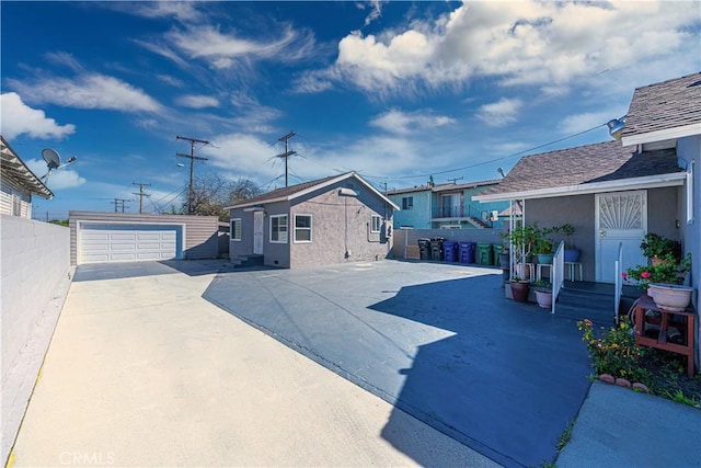 exterior space featuring an outbuilding, a detached garage, fence, and stucco siding