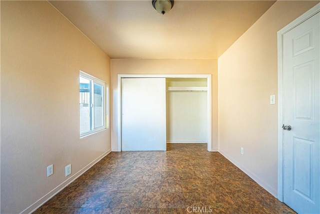 unfurnished bedroom with a closet, stone finish floor, and baseboards