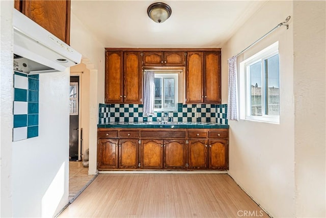 kitchen featuring tasteful backsplash, brown cabinets, a healthy amount of sunlight, and tile countertops