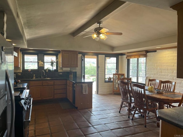 kitchen with dark countertops, ceiling fan, lofted ceiling with beams, stainless steel range, and a sink