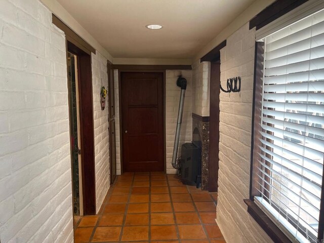 hallway featuring tile patterned floors and brick wall