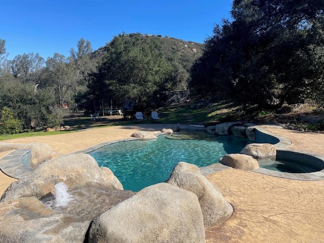 outdoor pool with a mountain view and an in ground hot tub