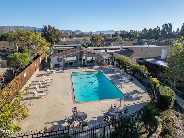 pool with a patio area, fence, and a mountain view