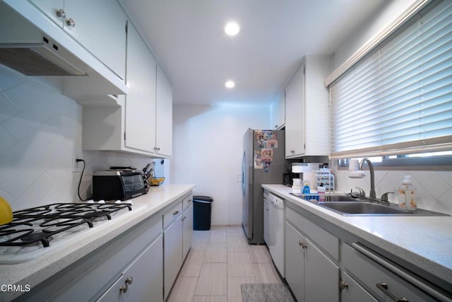 kitchen with light countertops, backsplash, white cabinets, a sink, and white appliances