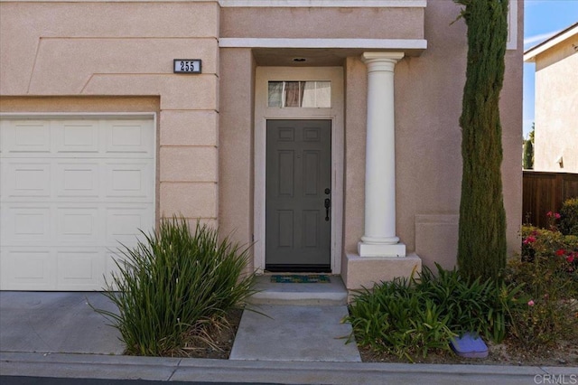 property entrance featuring a garage and stucco siding