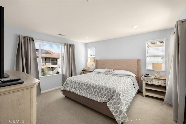 bedroom with visible vents, light carpet, and baseboards