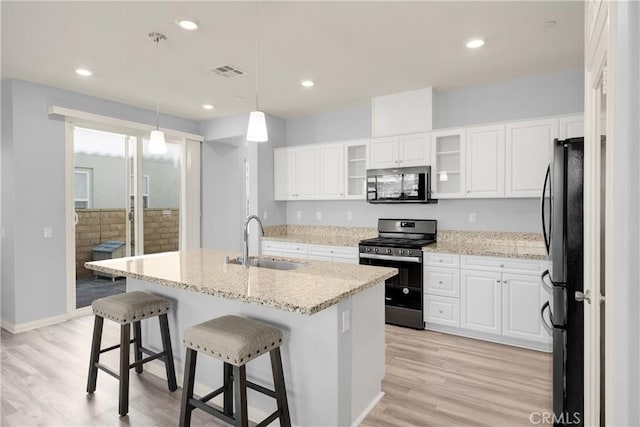 kitchen featuring a sink, visible vents, light wood-style floors, freestanding refrigerator, and gas range