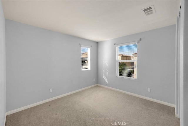 carpeted empty room featuring baseboards and visible vents