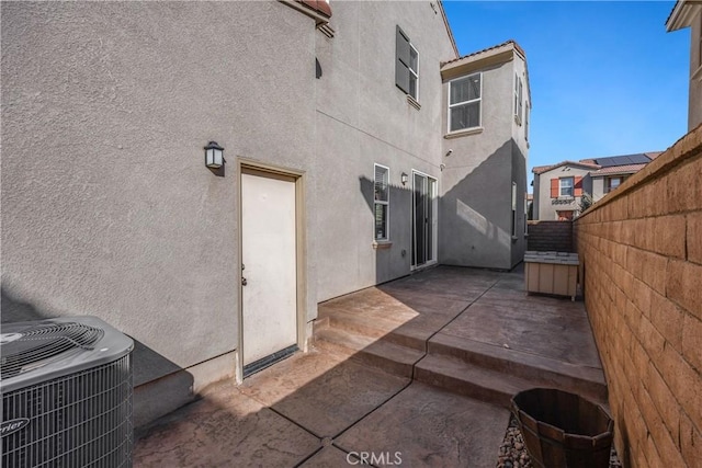 rear view of house featuring stucco siding, fence, cooling unit, and a patio