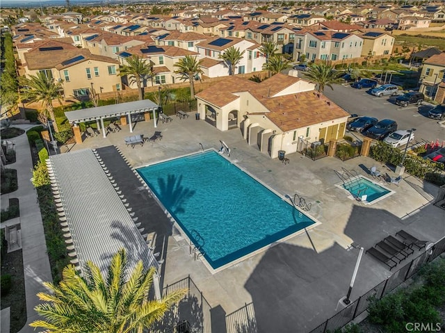 community pool with a patio area, fence, and a residential view