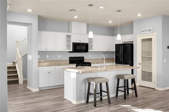 kitchen with light wood finished floors, visible vents, white cabinetry, a sink, and black appliances