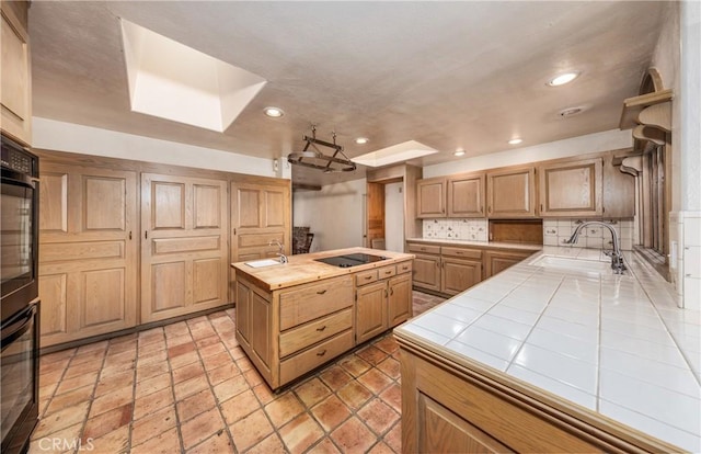 kitchen featuring black electric cooktop, recessed lighting, a skylight, a sink, and tile counters