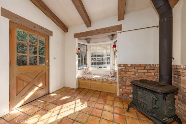 interior space with a wood stove, beam ceiling, and stone tile floors