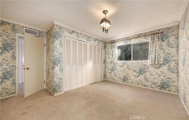 unfurnished bedroom featuring wallpapered walls, crown molding, visible vents, and a textured ceiling