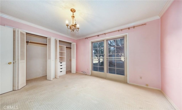 unfurnished bedroom featuring baseboards, ornamental molding, an inviting chandelier, carpet floors, and multiple closets