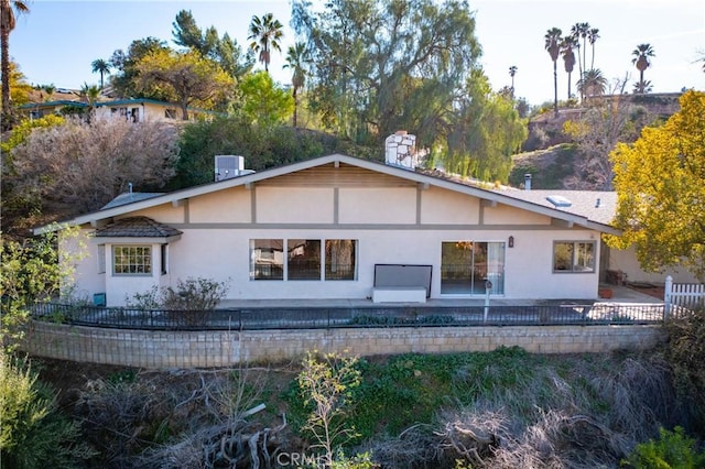 rear view of house featuring a patio area, fence, and stucco siding