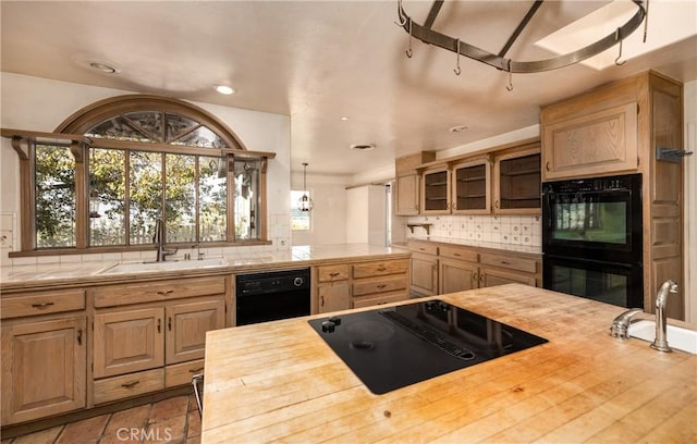 kitchen with decorative backsplash, a sink, black appliances, and wooden counters