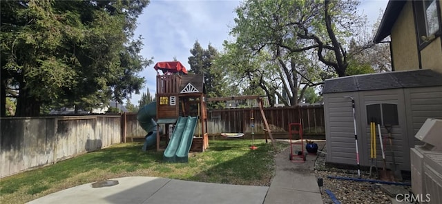 view of play area with a fenced backyard, a shed, a lawn, and an outbuilding