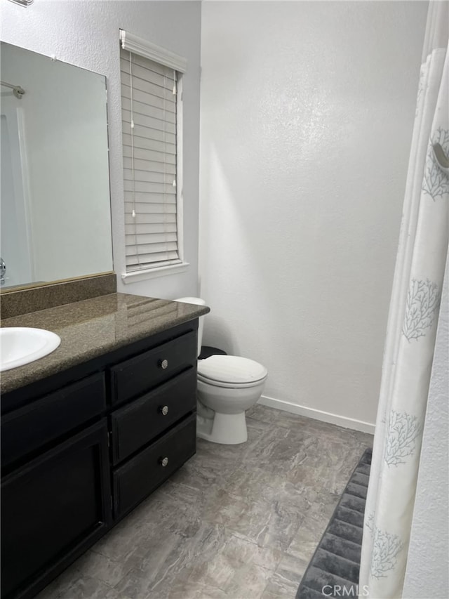 bathroom with vanity, toilet, and baseboards