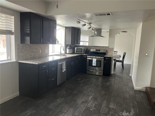 kitchen with visible vents, decorative backsplash, arched walkways, appliances with stainless steel finishes, and a sink