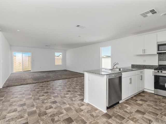 kitchen with stainless steel appliances, a peninsula, a sink, visible vents, and open floor plan