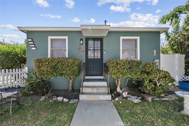 view of front facade with fence and stucco siding