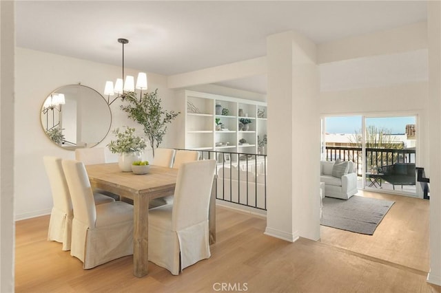 dining space featuring baseboards, light wood finished floors, and a notable chandelier