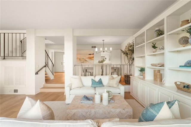 sitting room featuring light wood-style flooring, stairway, and a notable chandelier