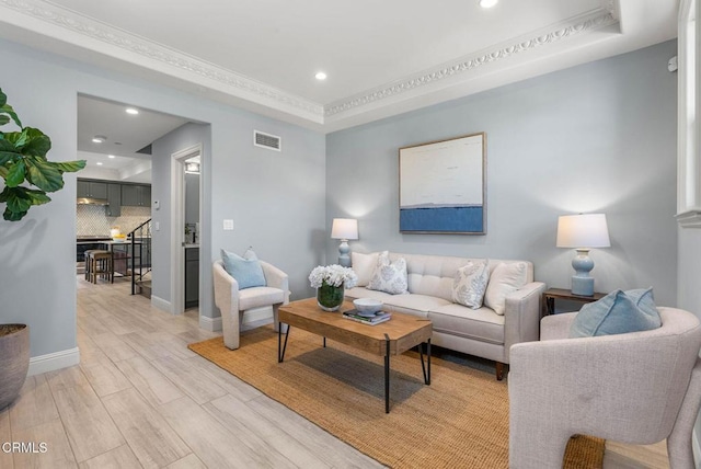 living room featuring light wood-style floors, a tray ceiling, visible vents, and recessed lighting