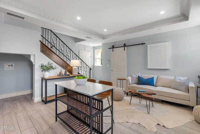 living area featuring visible vents, stairway, a barn door, wood tiled floor, and baseboards