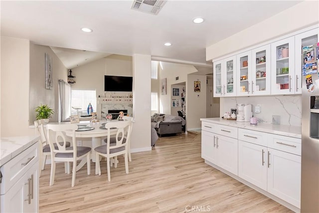 kitchen with white cabinets, vaulted ceiling, visible vents, and open floor plan