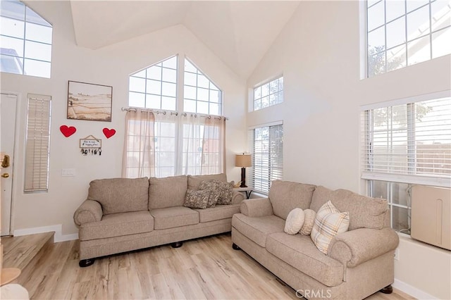 living room featuring high vaulted ceiling, baseboards, and wood finished floors