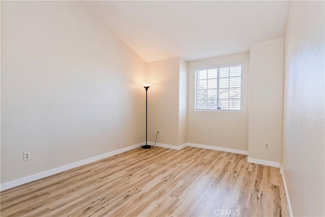 unfurnished room with lofted ceiling, light wood-style flooring, and baseboards