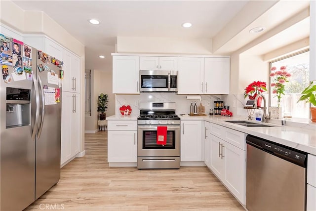 kitchen with light wood-style flooring, white cabinetry, stainless steel appliances, and a sink