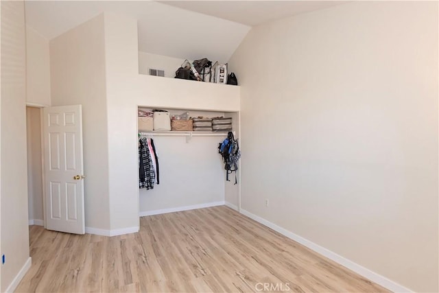 interior space with visible vents, vaulted ceiling, baseboards, and wood finished floors