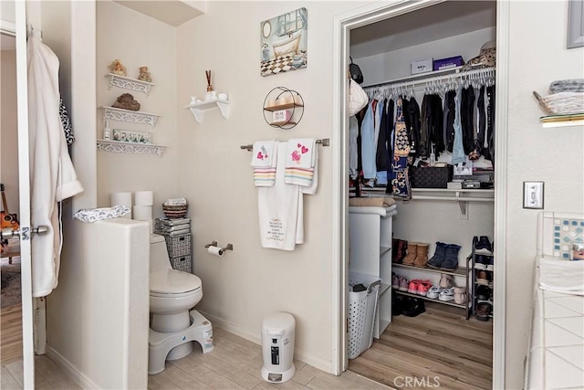 bathroom with toilet, baseboards, and wood finished floors