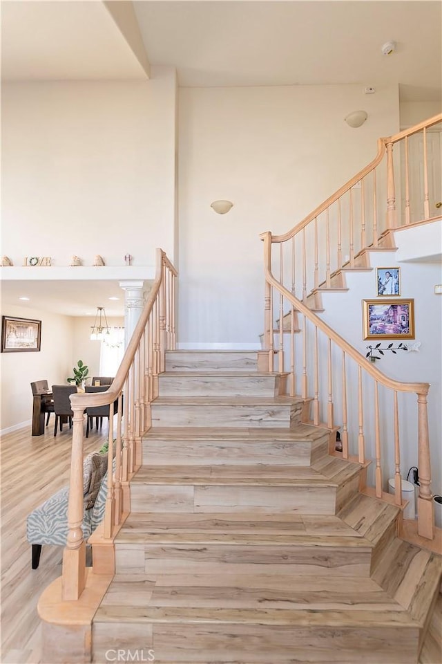 stairs featuring a high ceiling and wood finished floors