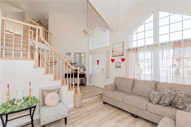 living area featuring stairs, high vaulted ceiling, wood finished floors, and visible vents