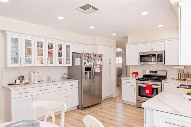 kitchen with stainless steel appliances, white cabinets, visible vents, and tasteful backsplash