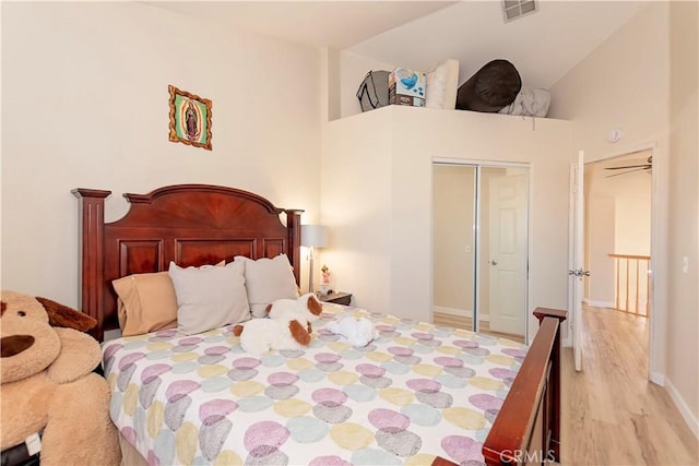 bedroom featuring a closet, visible vents, wood finished floors, high vaulted ceiling, and baseboards