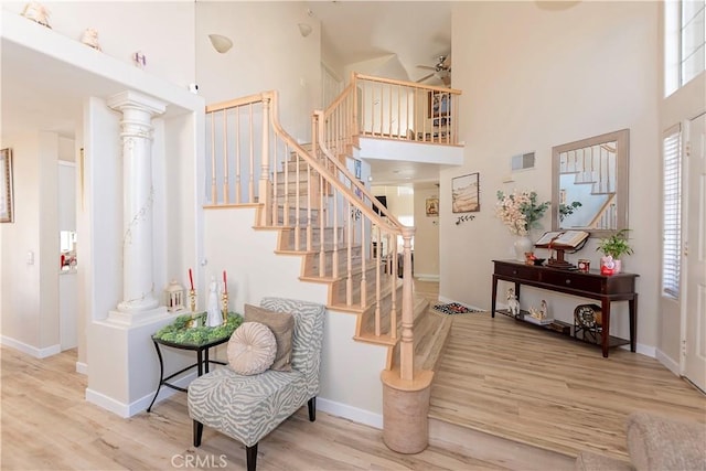 stairs with baseboards, visible vents, a high ceiling, and wood finished floors