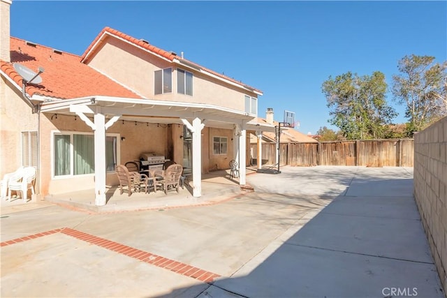 rear view of house with a tiled roof, a patio area, a fenced backyard, and stucco siding