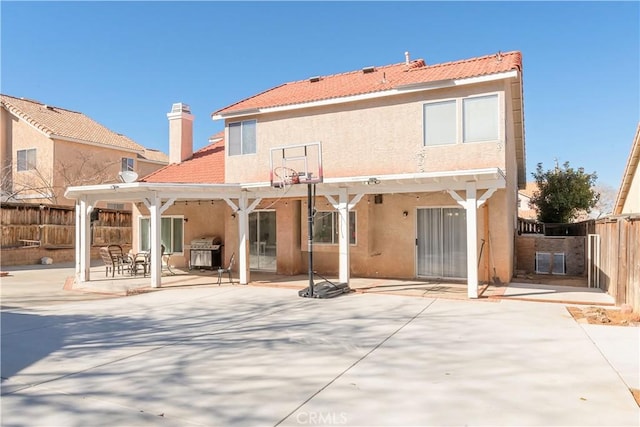 rear view of house with a patio area, fence, and stucco siding