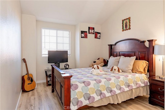 bedroom featuring light wood-style floors, lofted ceiling, and baseboards