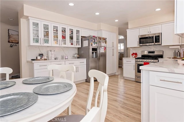 kitchen featuring stainless steel appliances, white cabinetry, and light wood finished floors